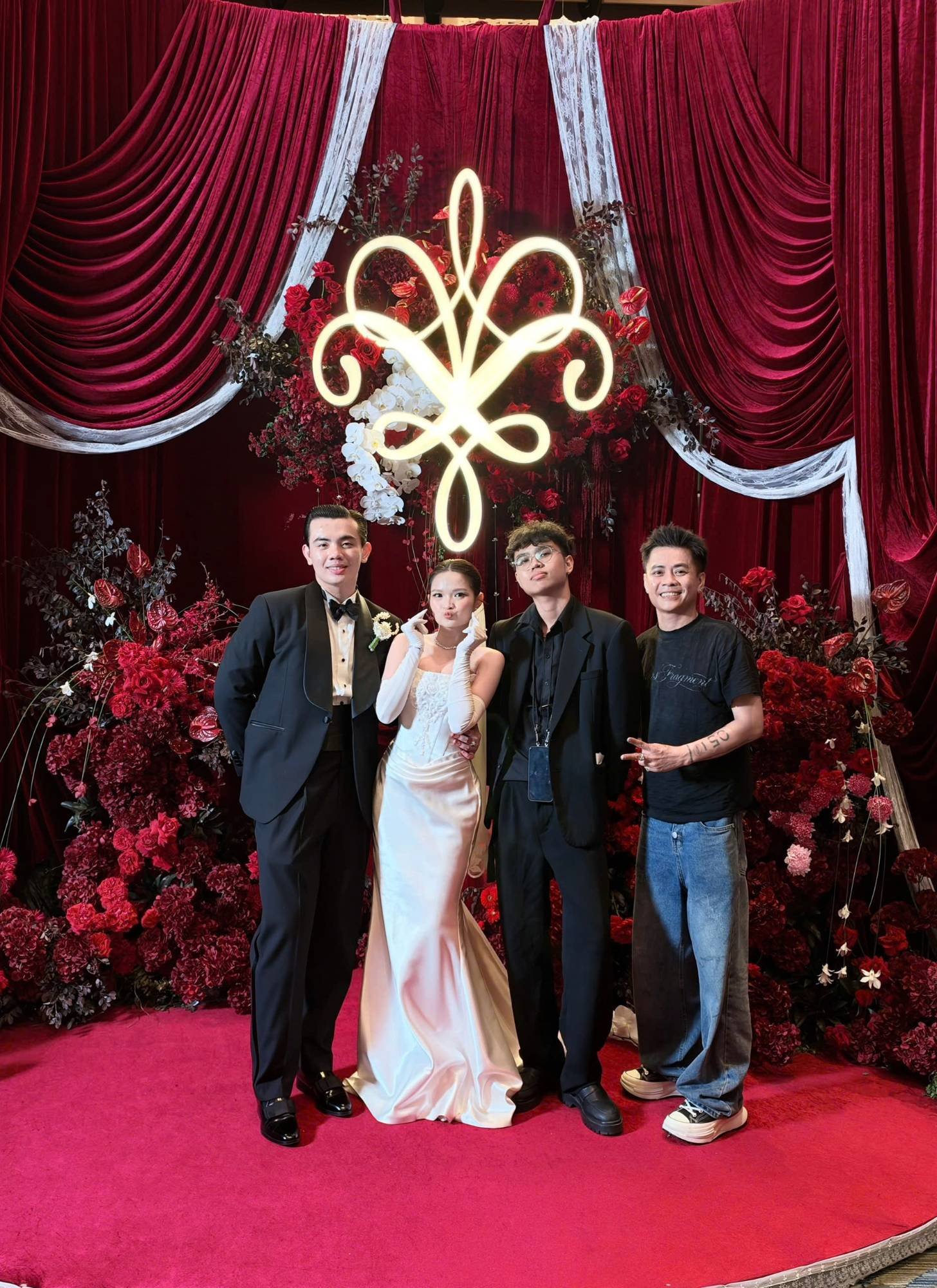 Cô dâu chú rể cùng ê-kíp trước backdrop monogram phát sáng