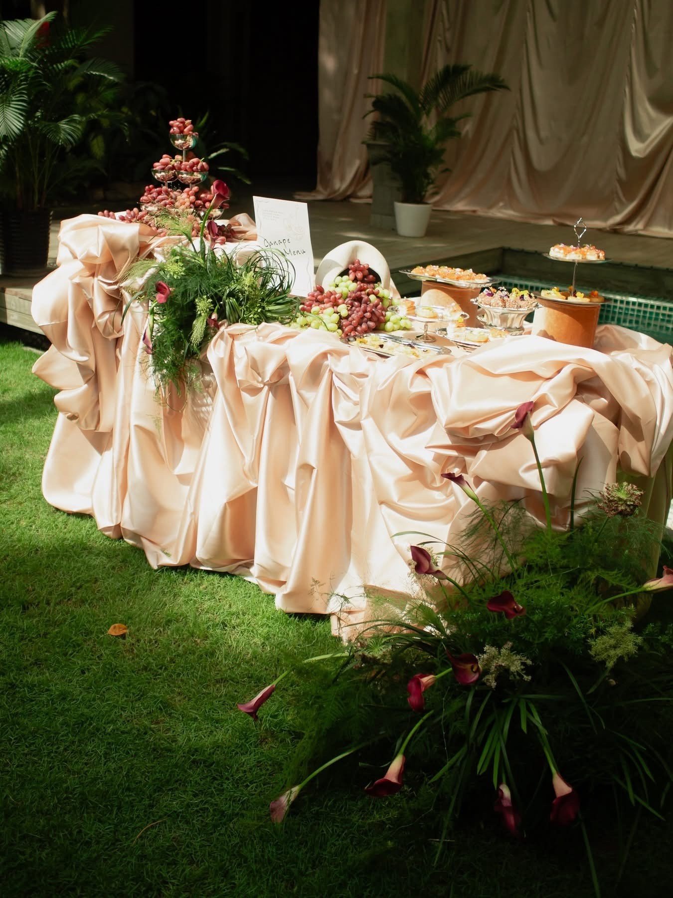 Bàn canapé thực tế phủ satin hồng phấn với nho và hoa calla