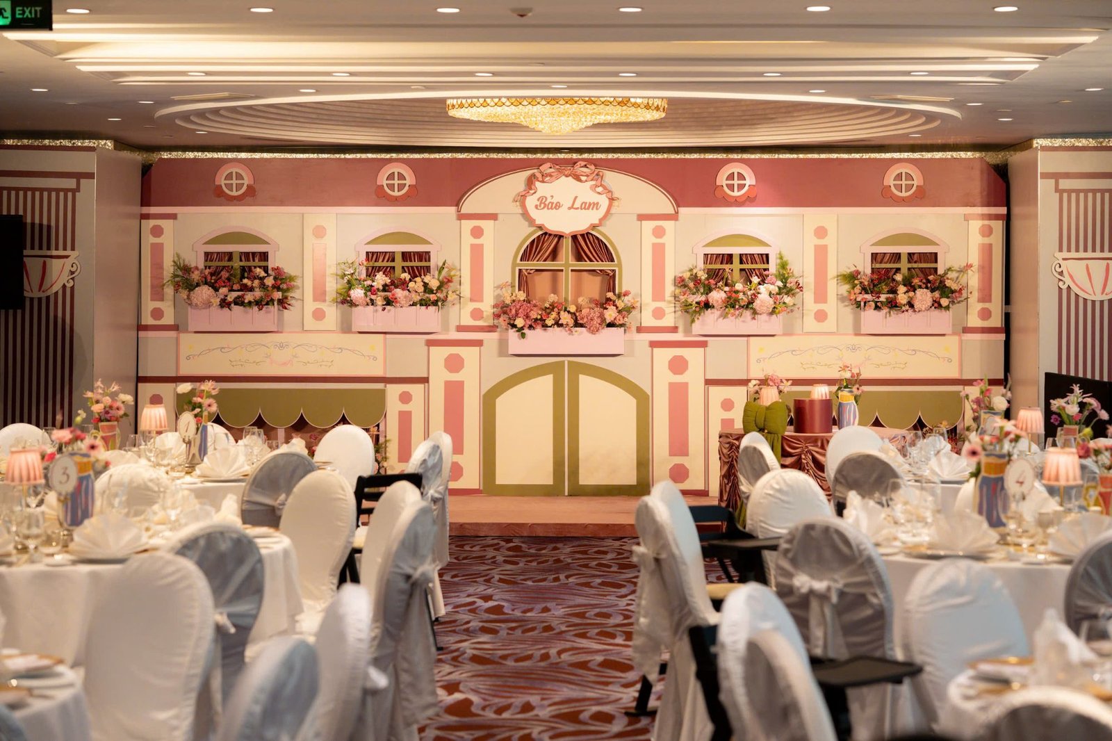 Sảnh tiệc thực tế với lối đi giữa các bàn tròn dẫn tới backdrop