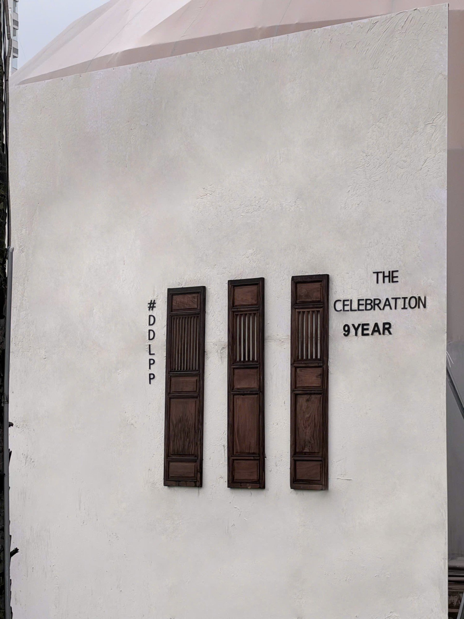 Ba cánh cửa gỗ cổ trên tường trắng với chữ The Celebration 9 Year