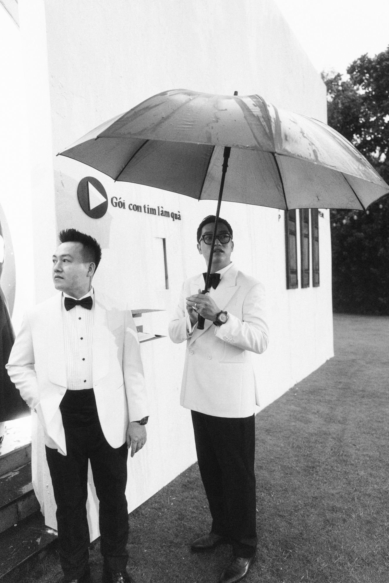 Ảnh đen trắng hai chú rể cầm ô cạnh chữ Gói con tim làm quà